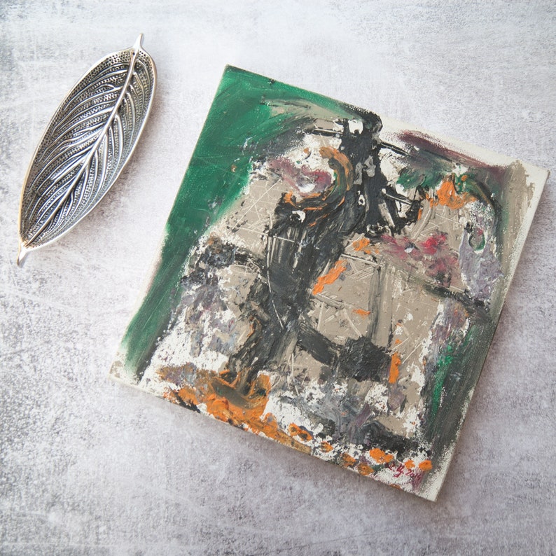 May include: Abstract painting on canvas with a green, black, white, orange, and gray color scheme. The painting has a textured surface and appears to be created with brushstrokes.