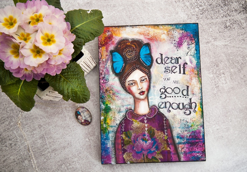 May include: A mixed media painting on canvas featuring a woman with blue butterfly hair clips. The painting has a colorful background and the text "dear self you are good enough" is written in black.