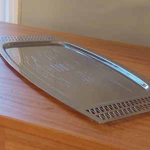 May include: A silver serving tray with a decorative design and a perforated edge.