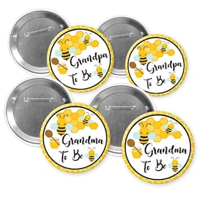 May include: A set of round pinback buttons with a bee theme. The buttons feature a honeycomb design, cartoon bees, and the text "Grandpa To Be" and "Grandma To Be" in black script. The buttons have a silver metal backing.