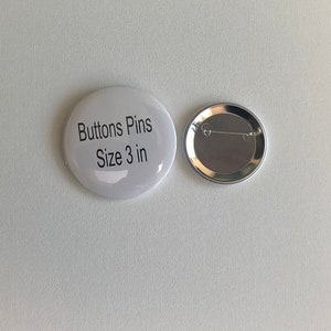 May include: Two white, round buttons with a pin back. One button has the text "Buttons Pins Size 3 in" printed in black. The other button shows the silver pin back. The buttons are on a white background.