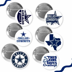 May include: A collection of white and silver pinback buttons featuring the Dallas Cowboys logo and text in navy blue. Designs include the team star, football, and the phrases "DALLAS COWBOYS" and "THIS GIRL loves Cowboys".