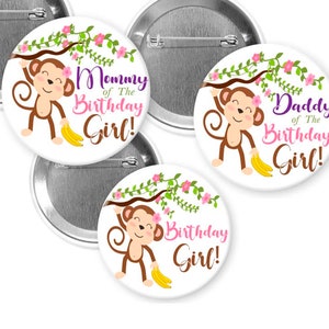 May include: White round pinback buttons with a cartoon monkey design. The monkey hangs from a floral branch and holds bananas. Text on the buttons reads "Mommy of The Birthday Girl!", "Daddy of The Birthday Girl!", and "Birthday Girl!"