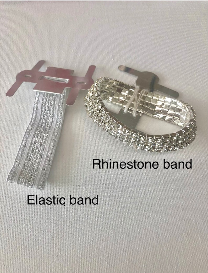 Pu&ograve; includere: L'immagine mostra due accessori: un elastico argentato e una fascia di strass. L'elastico &egrave; argentato e glitterato. La fascia di strass &egrave; composta da strass chiari e scintillanti. Il testo sull'immagine recita "Elastic band" e "Rhinestone band."