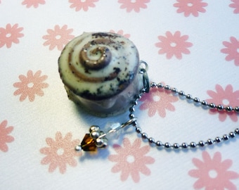 May include: A silver chain necklace with a brown and white swirl-shaped charm. The charm is attached to a clear crystal bead.
