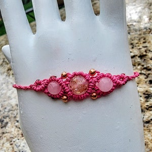 May include: Pink macrame bracelet with three pink and rose quartz beads and copper accents.