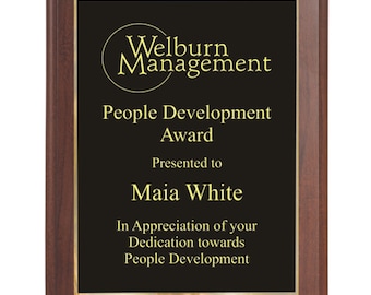 May include: A mahogany-framed plaque with a black background and gold lettering. The plaque reads "Welburn Management People Development Award Presented to Maia White In Appreciation of your Dedication towards People Development".