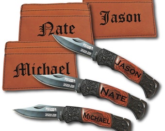 Może przedstawiać: Trzy spersonalizowane noże kieszonkowe z drewnianymi rękojeściami i skórzanymi etui. Noże są grawerowane nazwiskami "Jason", "Nate" i "Michael".