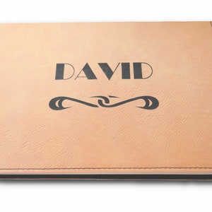 以下が含まれることがあります： 名前が「DAVID」と刻印された、薄い茶色の革製のジャーナル。ジャーナルには、名前の下に装飾的なデザインが施されています。