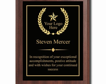 May include: A black plaque with a gold laurel wreath and star, a gold inscription that reads "Your Logo Here", and the name "Steven Mercer". The plaque has a gold border and the text "In recognition of your exceptional accomplishments, positive attitude and with wishes for your continued success" is written in gold.