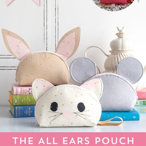 Può includere: Un modello di cucito per una pochette con quattro diversi design di orecchie di animali: coniglio, gatto, topo e granchio. Il modello include istruzioni per realizzare una pochette di granchio. L'immagine mostra le pochette finite in beige, bianco, grigio e rosa.