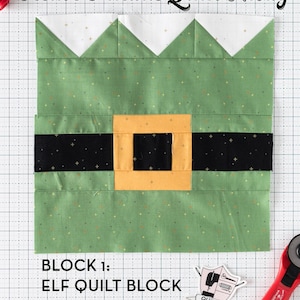Puede incluir: Un bloque de edredón verde y blanco con el texto "Festive Friends Quilt Along" y "Block 1: Elf Quilt Block". El bloque presenta un cuerpo verde con un cinturón negro y una hebilla dorada, y una parte superior blanca. Se ve un cortador rotatorio rojo y alfileres.