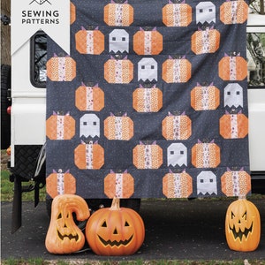 Peut inclure: Un modèle de courtepointe avec un motif de patchwork de citrouilles orange et de fantômes blancs sur un fond gris foncé. La courtepointe est affichée sur un véhicule et le texte "Pumpkin Patch Ghosts" et "Fat Quarter Friendly" est affiché sous la courtepointe.