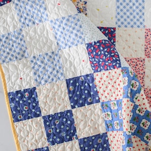 May include: A patchwork quilt with a variety of patterned squares in white, blue, and floral prints. The quilt features a yellow border and is quilted with a floral pattern. The quilt is made of cotton and is approximately 60 inches by 60 inches.