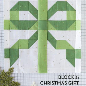 May include: A green and white quilt block with a Christmas gift design. The block is made up of squares and triangles, and the gift is tied with a green ribbon. The text "BLOCK 5: CHRISTMAS GIFT QUILT BLOCK" is printed below the block.