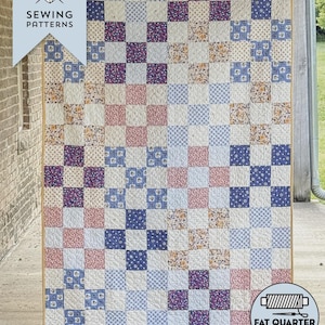 May include: A patchwork quilt with a checkerboard pattern in shades of blue, purple, pink, and cream. The quilt is made of various floral and patterned fabrics. The text "GATHERED QUARTERS QUILT" is at the bottom.