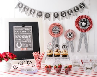 May include: A Kentucky Derby themed party table setting with red and white checkered tablecloths, red and white striped paper straws, cupcakes with black and white horseshoe toppers, and red and white rosettes with black and white stripes. The table also features a chalkboard sign with the text "Kentucky Derby Go Baby Go Run for the Roses Lucky Wear Your Hat Churchill Downs Jockey Silks Derby Pie".