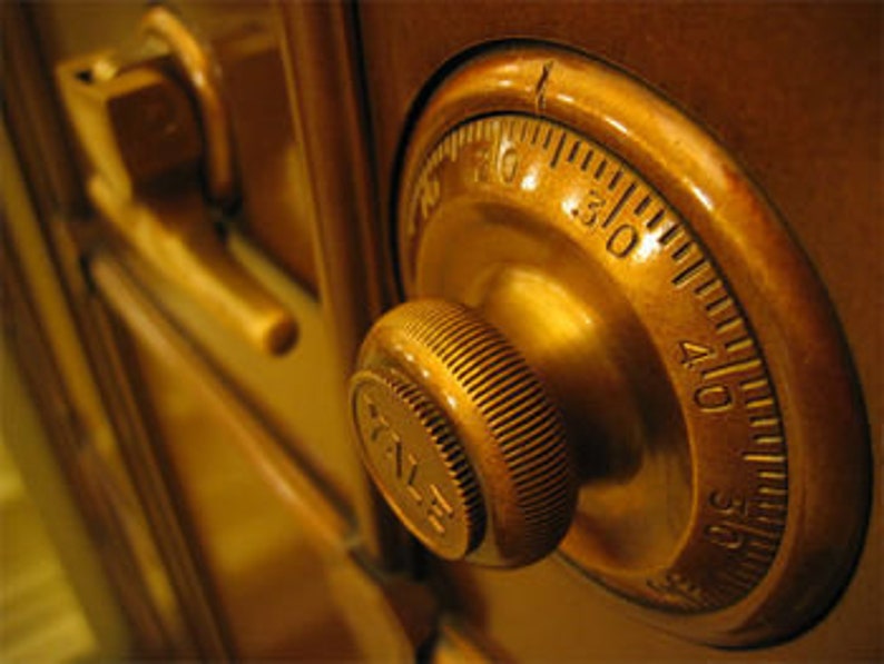 Puede incluir: Primer plano de una cerradura de combinaci&oacute;n de lat&oacute;n en una puerta de caja fuerte marr&oacute;n. La cerradura tiene un dial con n&uacute;meros del 0 al 40 y una perilla para girar el dial.