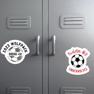 May include: Two locker decals with soccer ball graphics. The left decal is white with black text that reads "2023 Wolfpack Diego #12". The right decal is white with red text that reads "Aidan #8 Timberwolves".