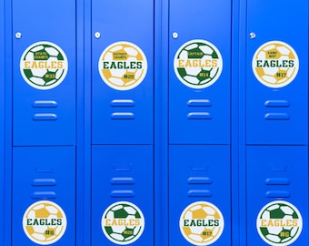 Puede incluir: Ocho puertas de casilleros azules con imanes de balón de fútbol amarillo y verde. Los imanes tienen la palabra "EAGLES" y un número. Los números en los imanes son 33, 25, 14, 17, 8, 20, 17 y 6.