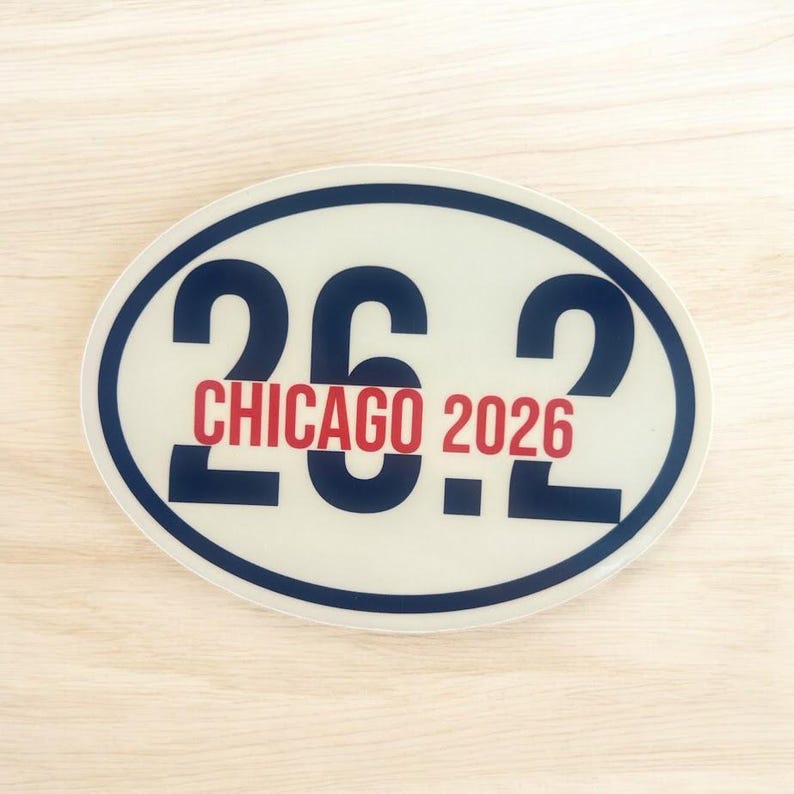 Puede incluir: Una pegatina ovalada con el texto "26.2 CHICAGO 2026". Los n&uacute;meros "26.2" son de color azul marino, con "CHICAGO 2026" en rojo. La pegatina tiene un fondo blanco y un borde azul marino. Ideal para corredores de marat&oacute;n.