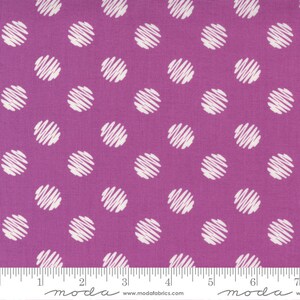 May include: Close-up of a fabric with a repeating pattern of white scribbled circles on a purple background. The fabric has a textured appearance. A ruler is at the bottom of the image.