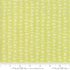 May include: Green fabric with a white alphabet pattern. The fabric has a ruler with the word "moda" printed on it.
