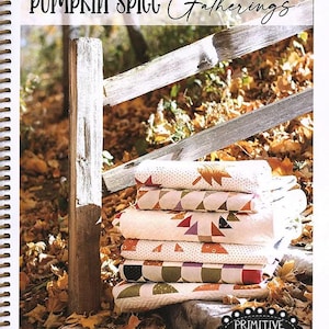 May include: A stack of six folded quilts with various geometric patterns in fall colors. The quilts are on a stone surface with autumn leaves. The cover reads "Pumpkin Spice Gatherings" and "Primitive Gatherings".