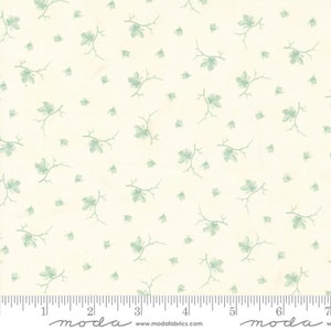May include: A white fabric with a repeating pattern of small green leaves and branches. The fabric has a subtle texture and a light, airy feel. The fabric is marked with a ruler in inches and the words "moda" and "www.modafabrics.com".