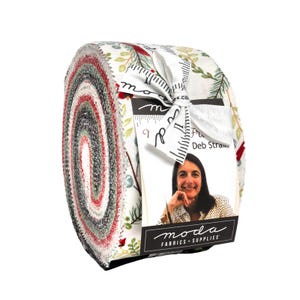 May include: Rolled fabric bundle with patterned fabrics in red, green, and white. The bundle is tied with a white ribbon and a tag with a woman's photo and the words "moda FABRICS + SUPPLIES".
