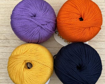 May include: Four balls of yarn in different colors: purple, orange, yellow, and navy blue. The yarn is wound into balls and ready for knitting or crocheting.