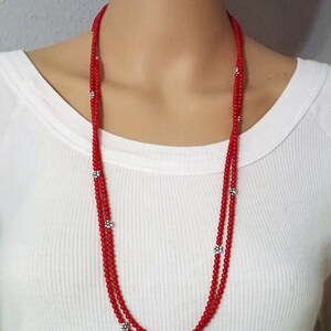Puede incluir: Un collar de doble cadena hecho de cuentas rojas con acentos de flores plateadas.