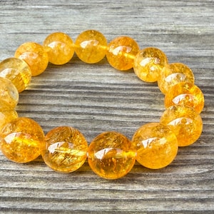 May include: A bracelet made of round, orange citrine beads. The beads are translucent and have a slight sparkle.
