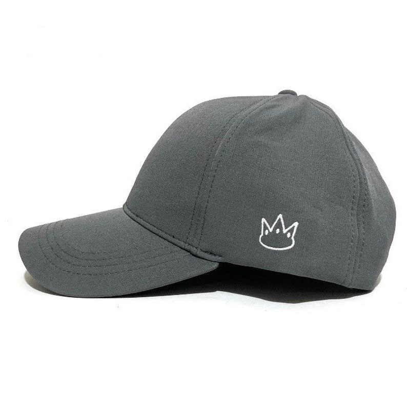 May include: A grey baseball cap with a white crown embroidered on the front.