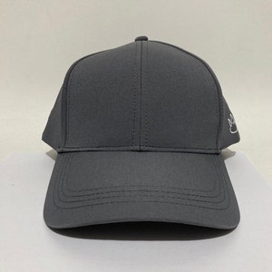 May include: A dark grey baseball cap with a white embroidered logo on the side.
