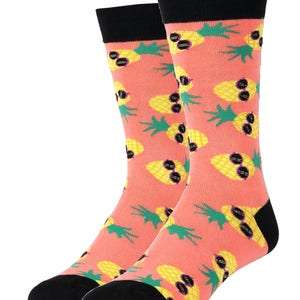 Puede incluir: Un par de calcetines de color rosa coral con un patr&oacute;n de pi&ntilde;as amarillas que llevan gafas de sol. Los calcetines tienen dedos y talones negros.