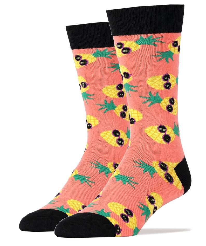 Puede incluir: Un par de calcetines de color rosa coral con un patr&oacute;n de pi&ntilde;as amarillas que llevan gafas de sol. Los calcetines tienen dedos y talones negros.