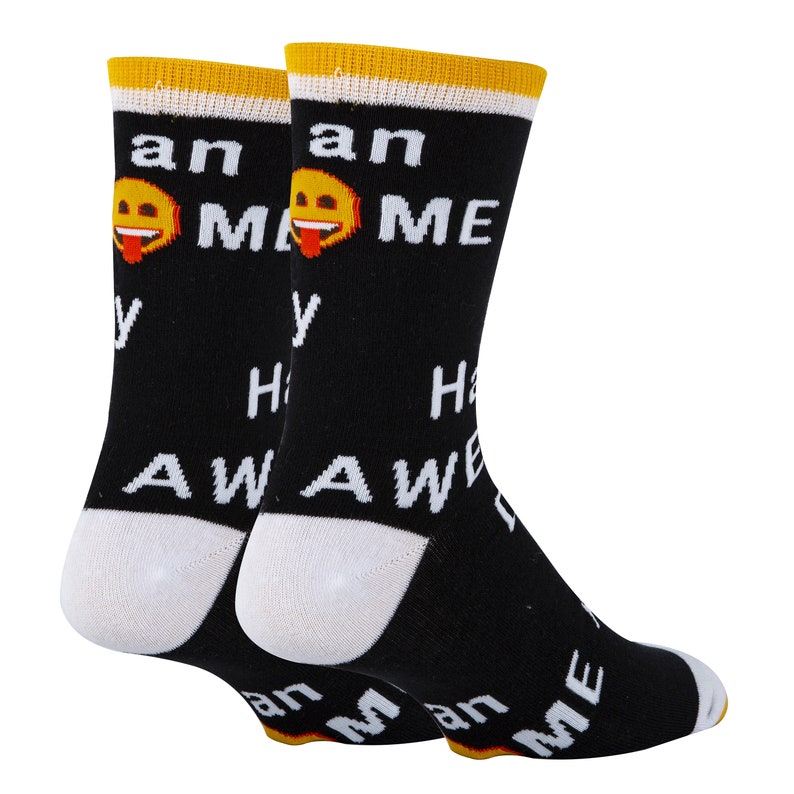 Puede incluir: Calcetines negros con un dise&ntilde;o blanco y amarillo. Los calcetines presentan un emoji sonriente con la lengua fuera y el texto "Puedo hacerte feliz con memes, vamos".