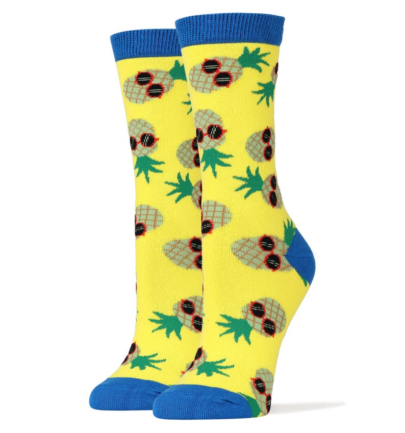 Puede incluir: Un par de calcetines amarillos con un patr&oacute;n de pi&ntilde;as que llevan gafas de sol. Los calcetines tienen pu&ntilde;os azules.