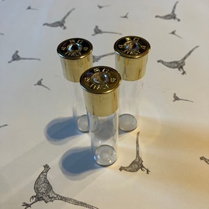 May include: Three clear glass tubes with gold-colored tops. The tops are labeled "20 GA 12" and have a small, clear window in the center.