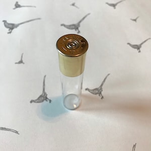 Könnte beinhalten: Ein klares Glasrohr mit einem goldenen Metalldeckel. Der Deckel trägt die Aufschrift "LYMAN" und "12".