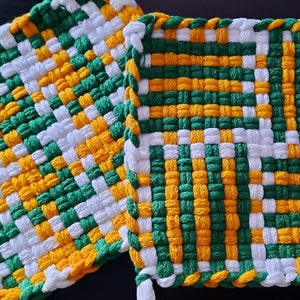 May include: Two square woven pot holders in green, white and yellow. The pot holders are made with a simple woven pattern.