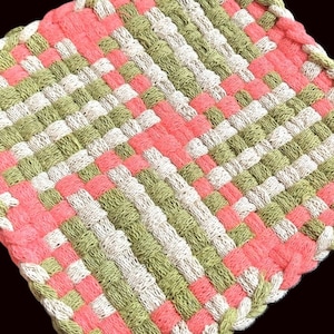 May include: A woven pot holder with a checkered pattern in pink, green and white.