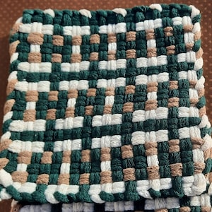 May include: A square woven coaster with a green, brown, and white checkered pattern.