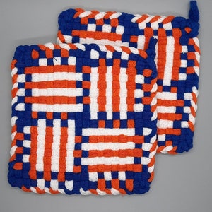 May include: Two woven pot holders in a blue, white, and orange checkered pattern. The pot holders are made of thick, woven fabric and have a loop for hanging.