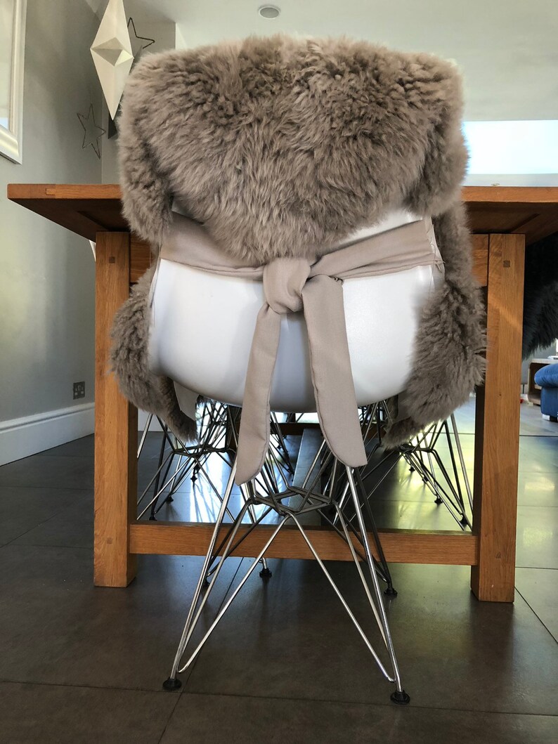 May include: A brown faux fur chair cushion with a white tie. The cushion is tied around a white chair with a chrome base.