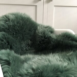 May include: A soft, plush, green sheepskin rug. The rug is made of natural sheepskin and has a long, fluffy pile.