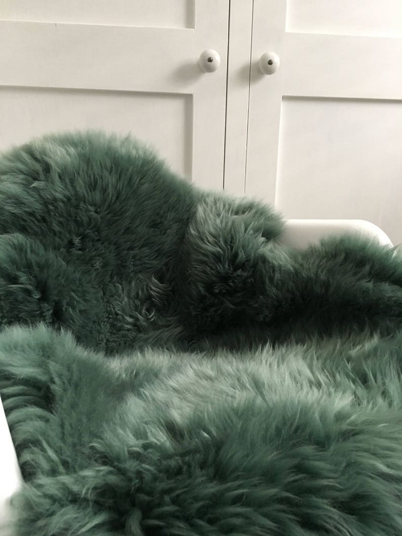 May include: A soft, plush, green sheepskin rug. The rug is made of natural sheepskin and has a long, fluffy pile.