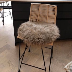 May include: A black metal bar stool with a woven cane seat and a fluffy gray sheepskin cushion.