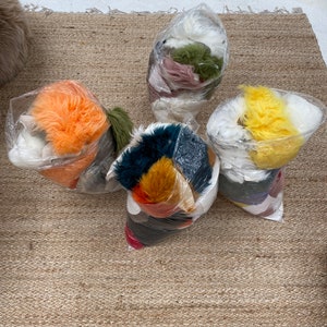 May include: Five bags of colorful faux fur, each containing different colors and textures. The bags are arranged on a light brown woven rug.